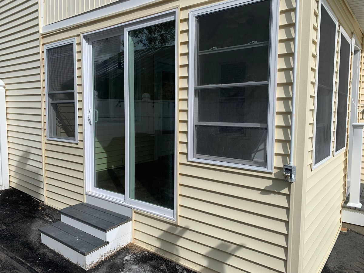 A yellow house with a screened in porch and stairs