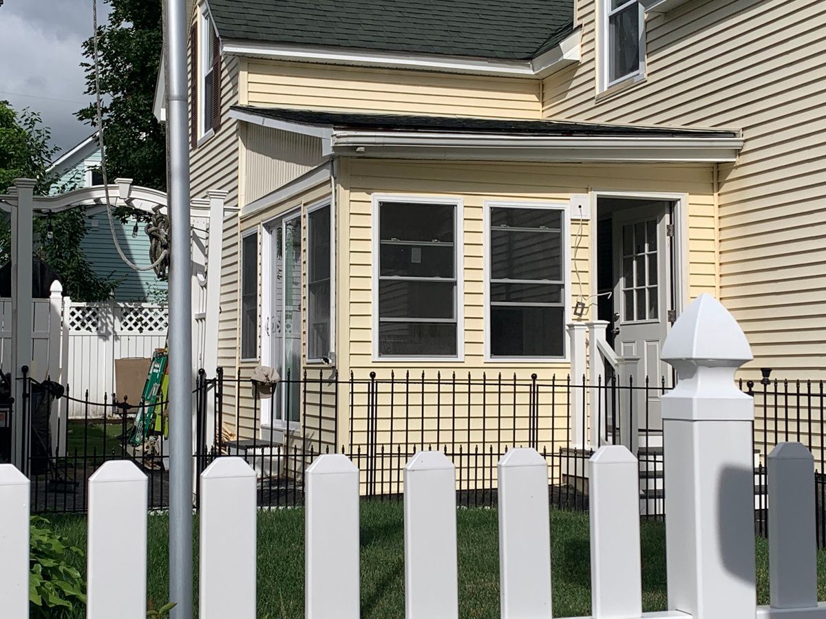 A yellow house with a white picket fence in front of it.