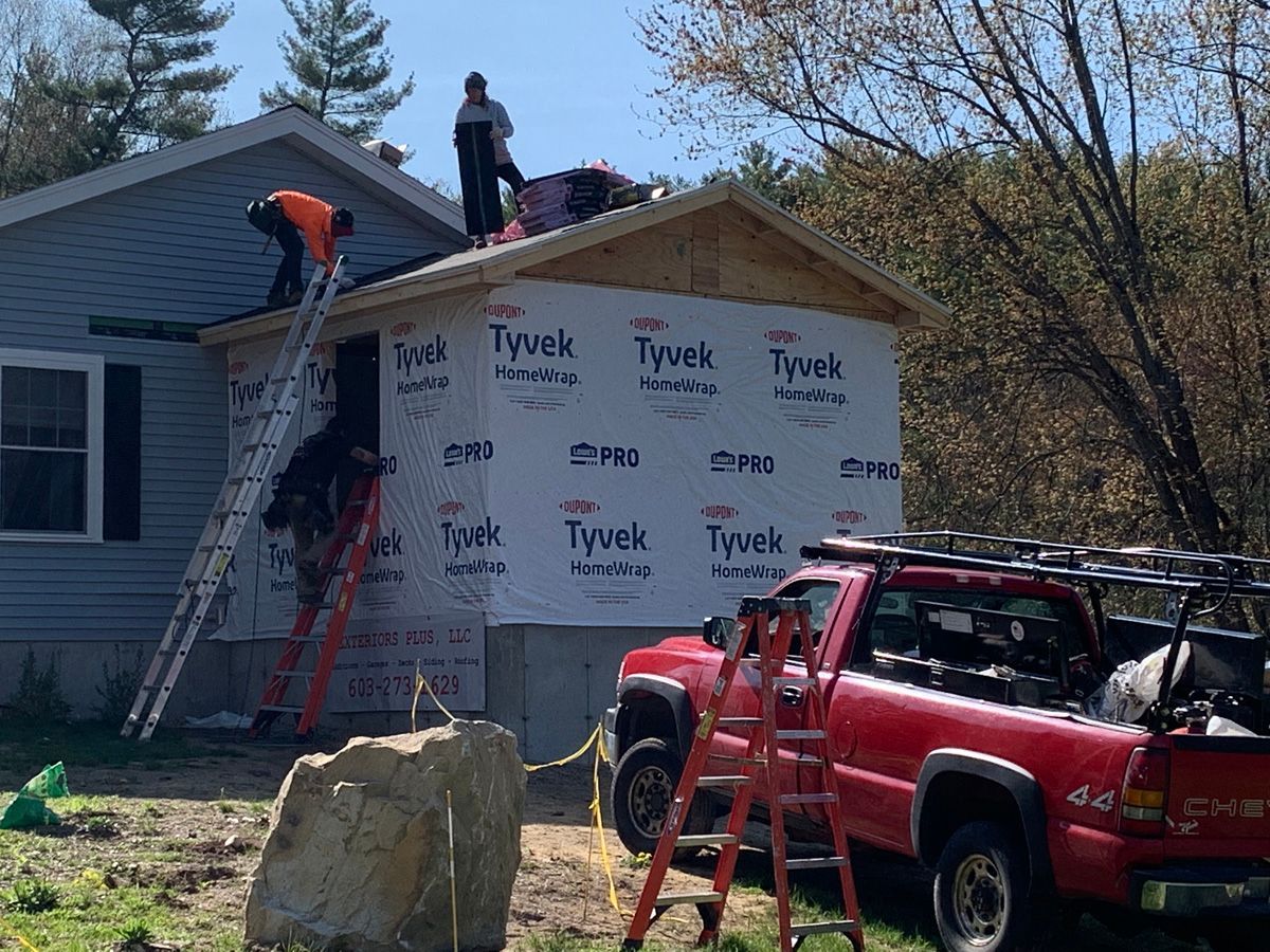 A red truck is parked in front of a house under construction.