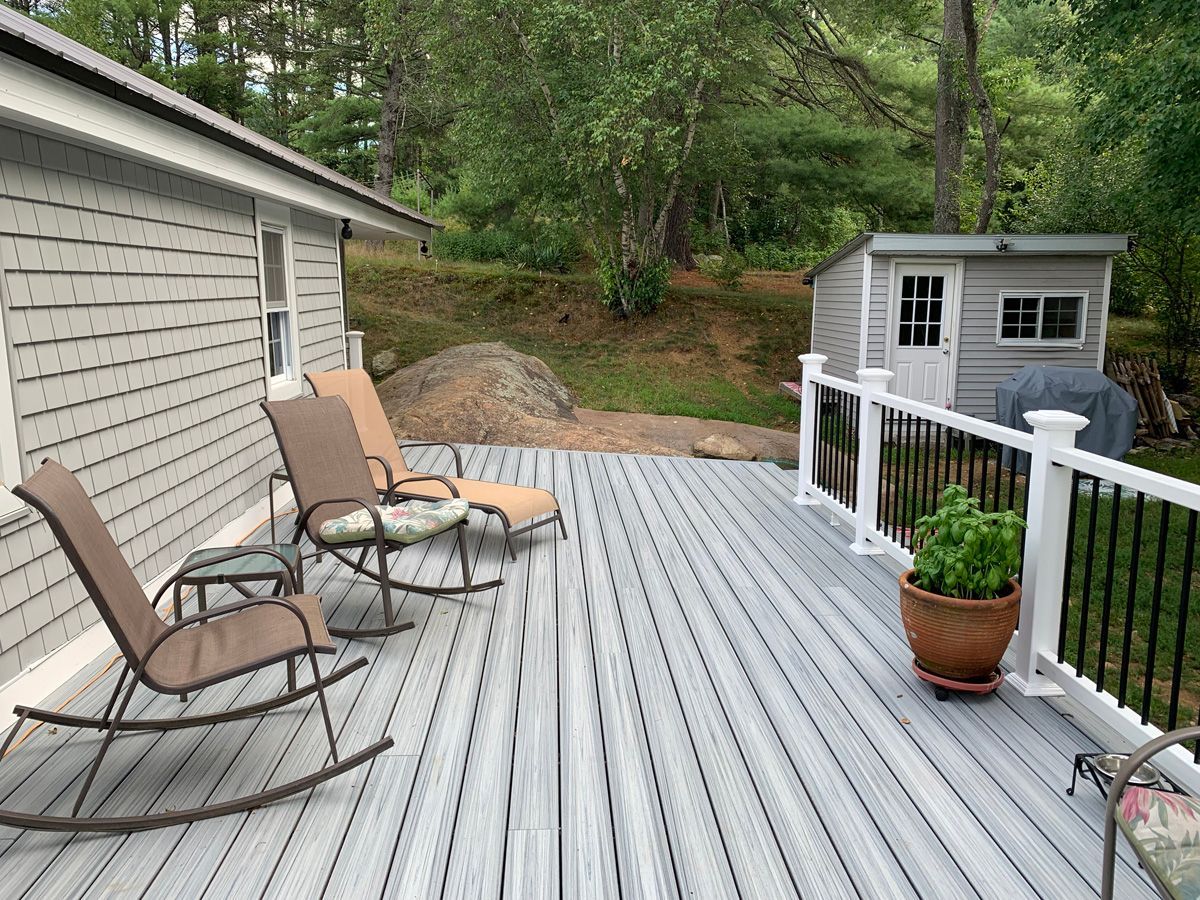 A deck with rocking chairs and a potted plant on it