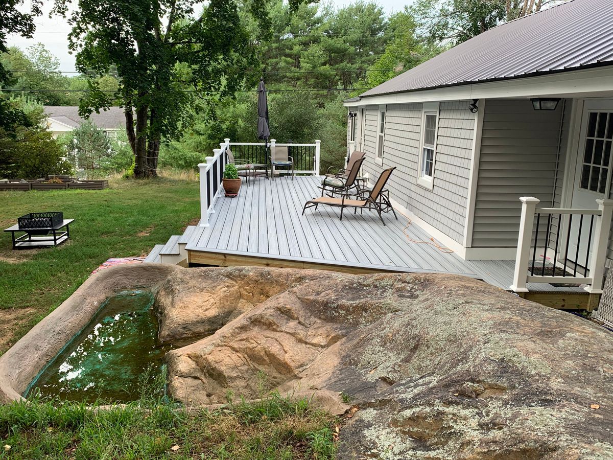 A house with a large deck and chairs on it.