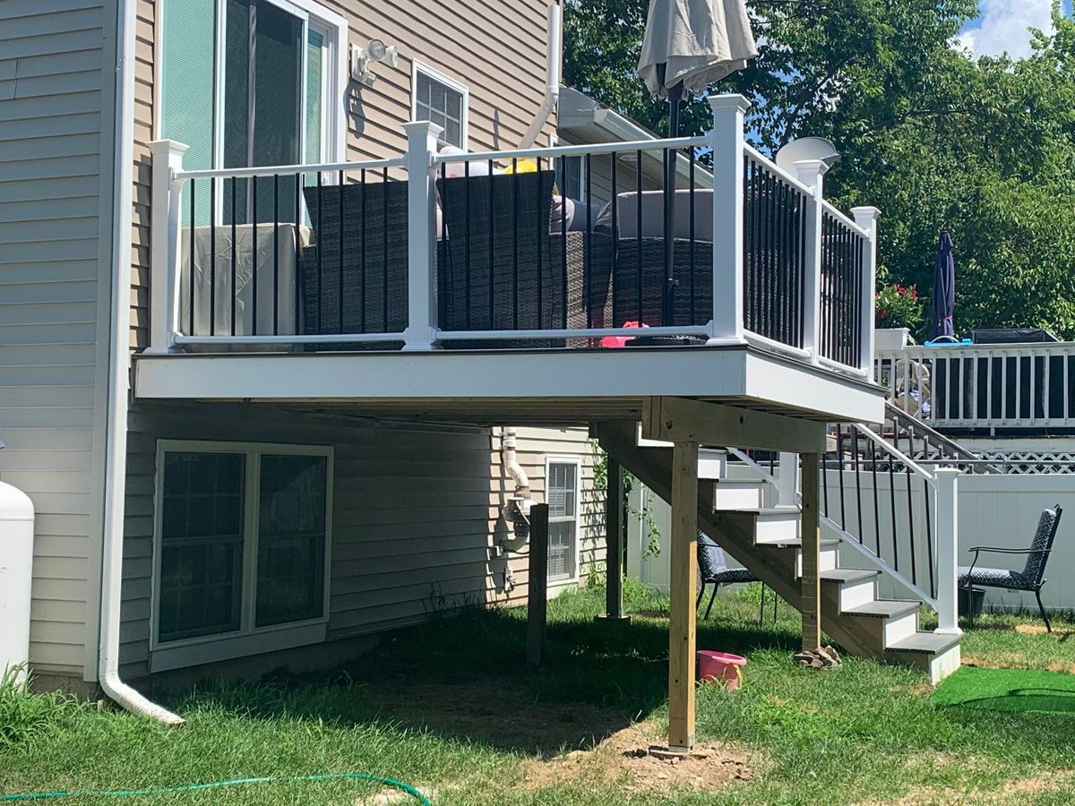 A deck with stairs leading up to it is in the backyard of a house.