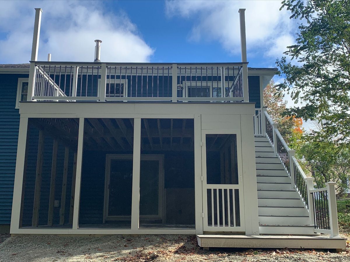 A blue house with a screened in porch and stairs
