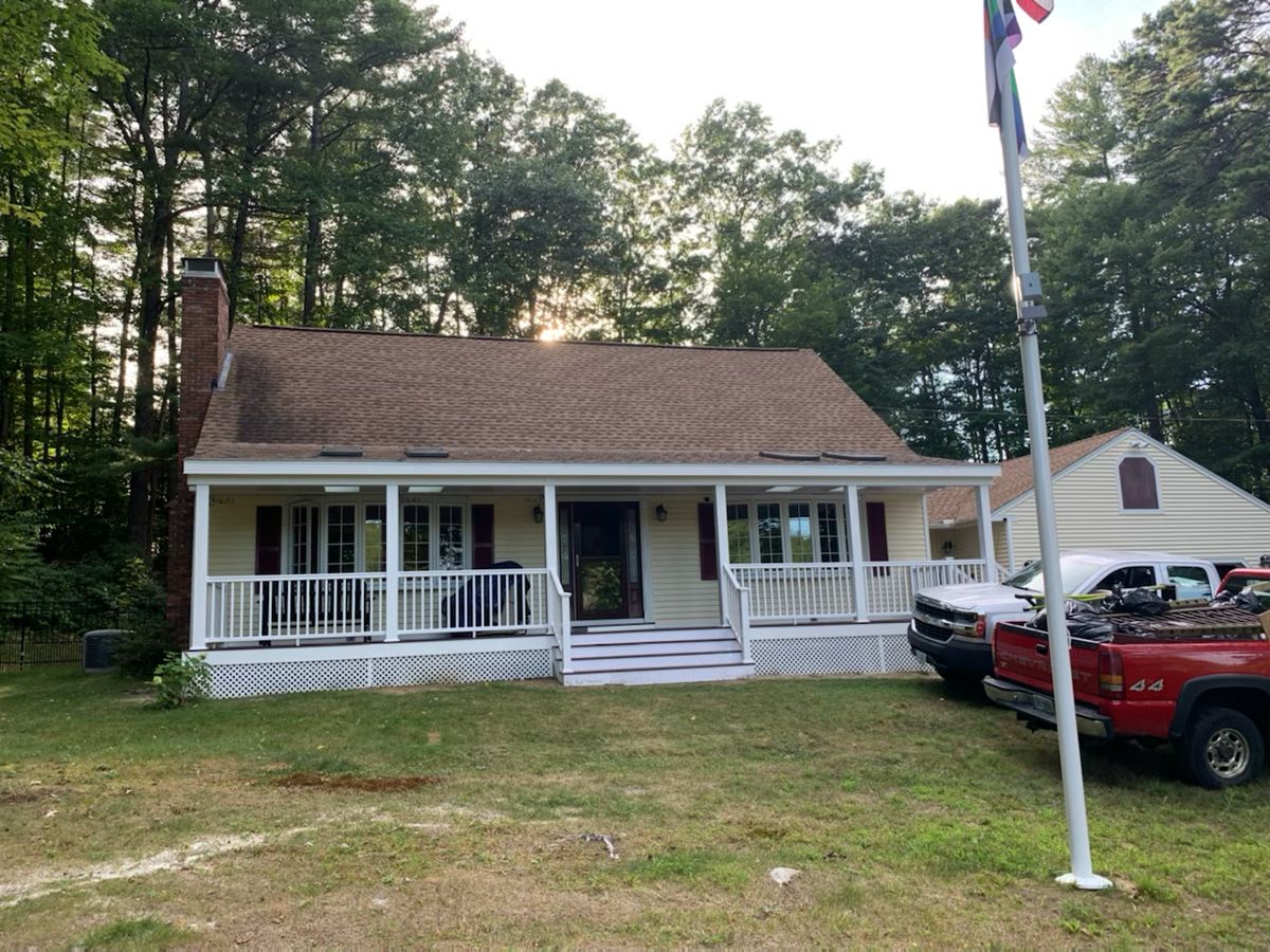 A red truck is parked in front of a house with a porch.