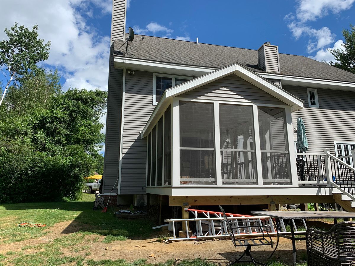 A screened in porch is being built on the side of a house.