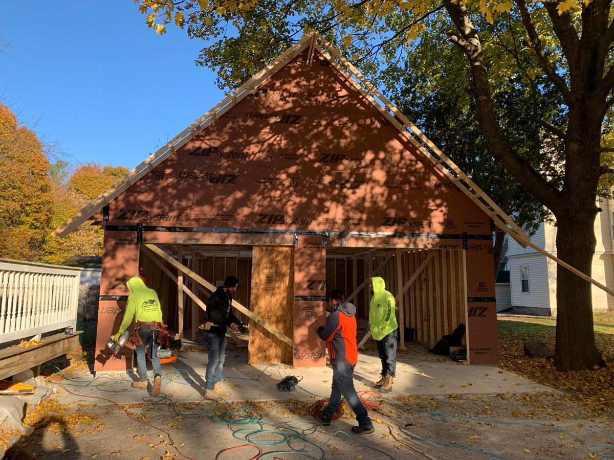 A group of construction workers are working on a garage under construction.