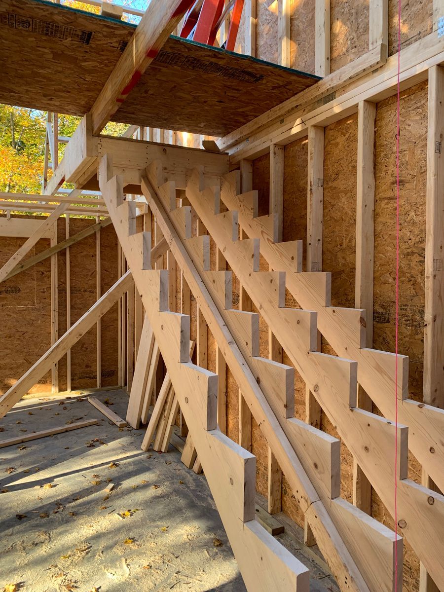 A wooden staircase is being built in a house under construction.
