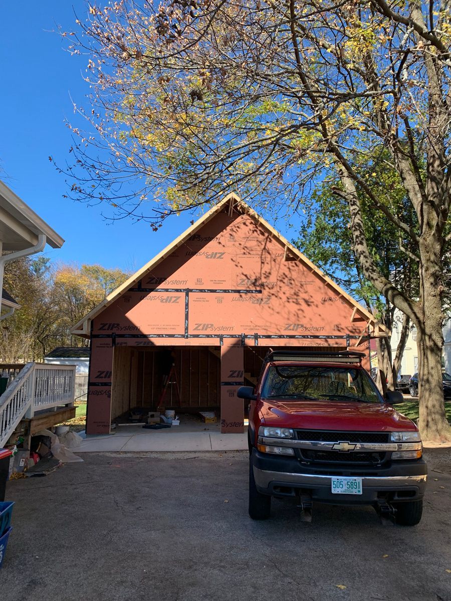 A red truck is parked in front of a garage under construction.