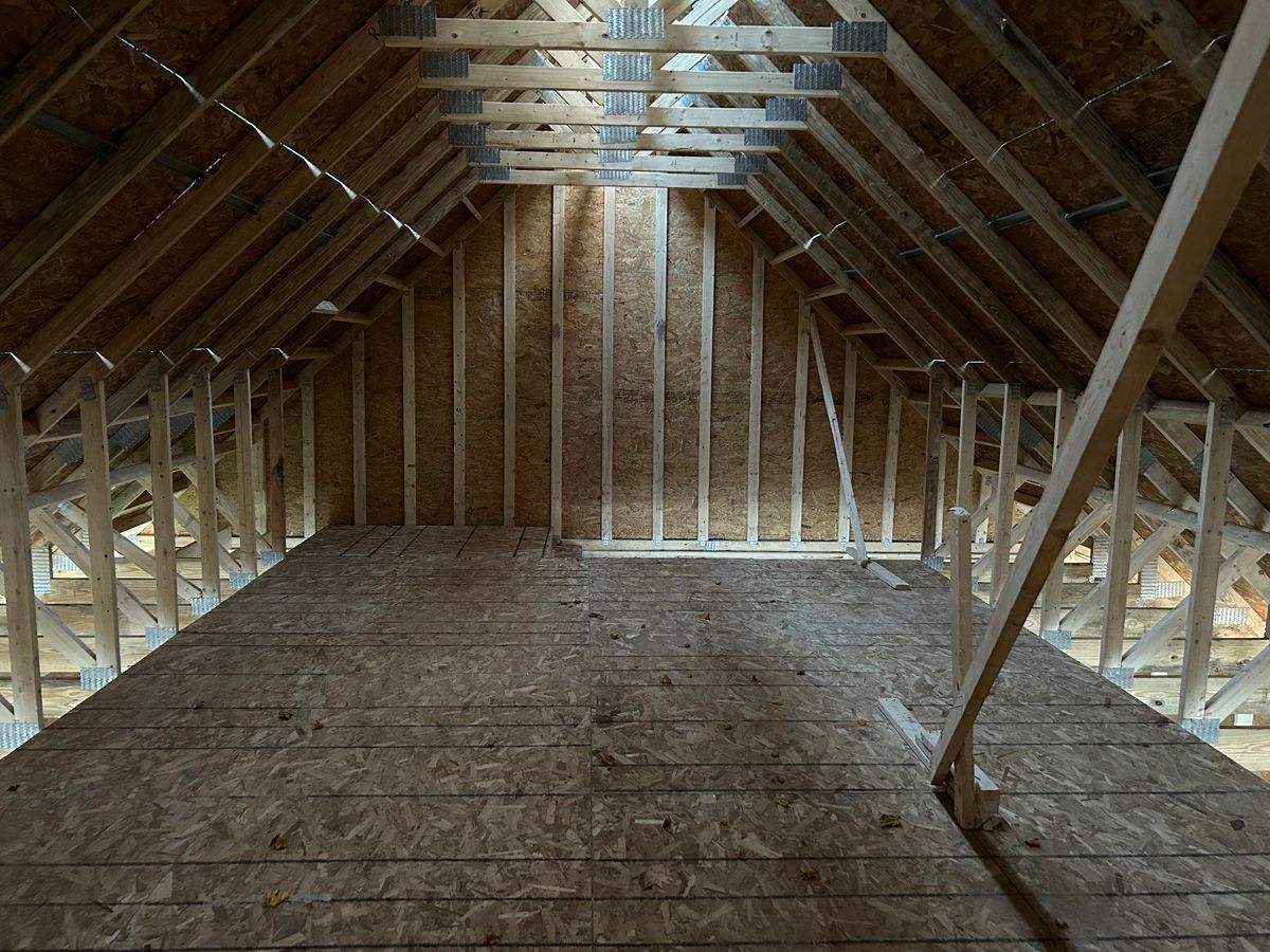 An empty attic with wooden beams and a wooden floor