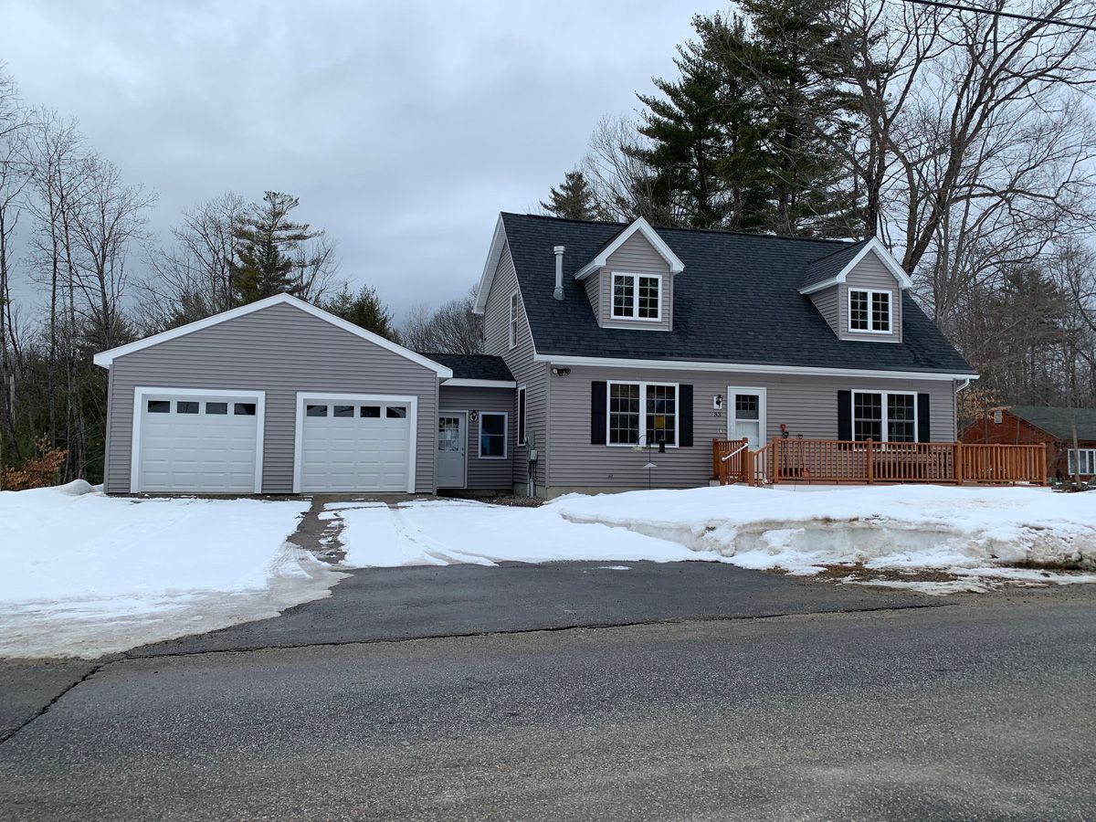 A house with a garage and a driveway covered in snow