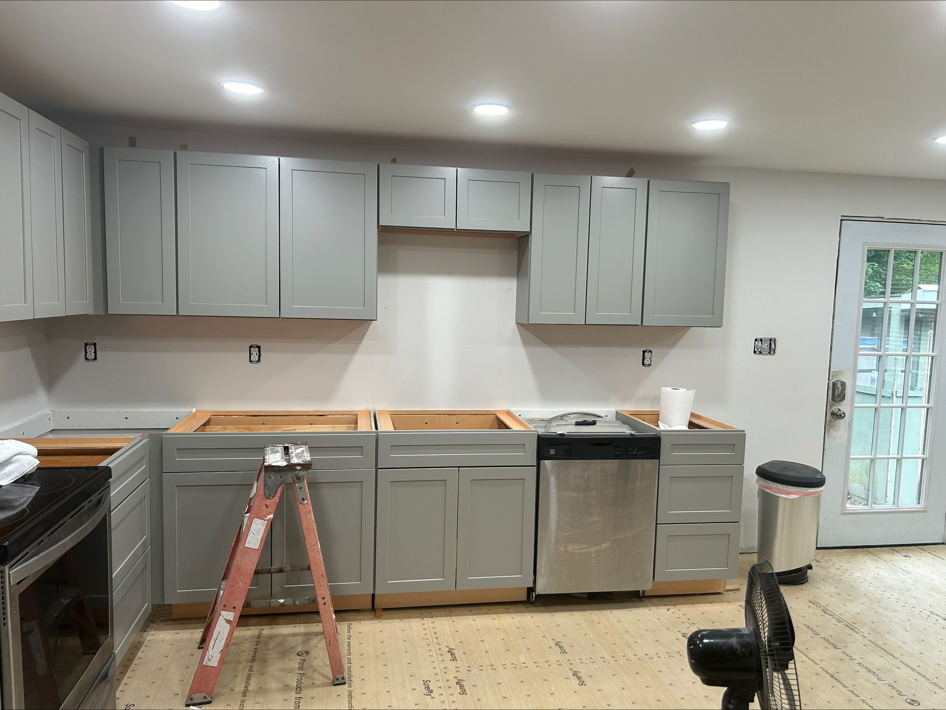 A kitchen with gray cabinets and stainless steel appliances is being remodeled.
