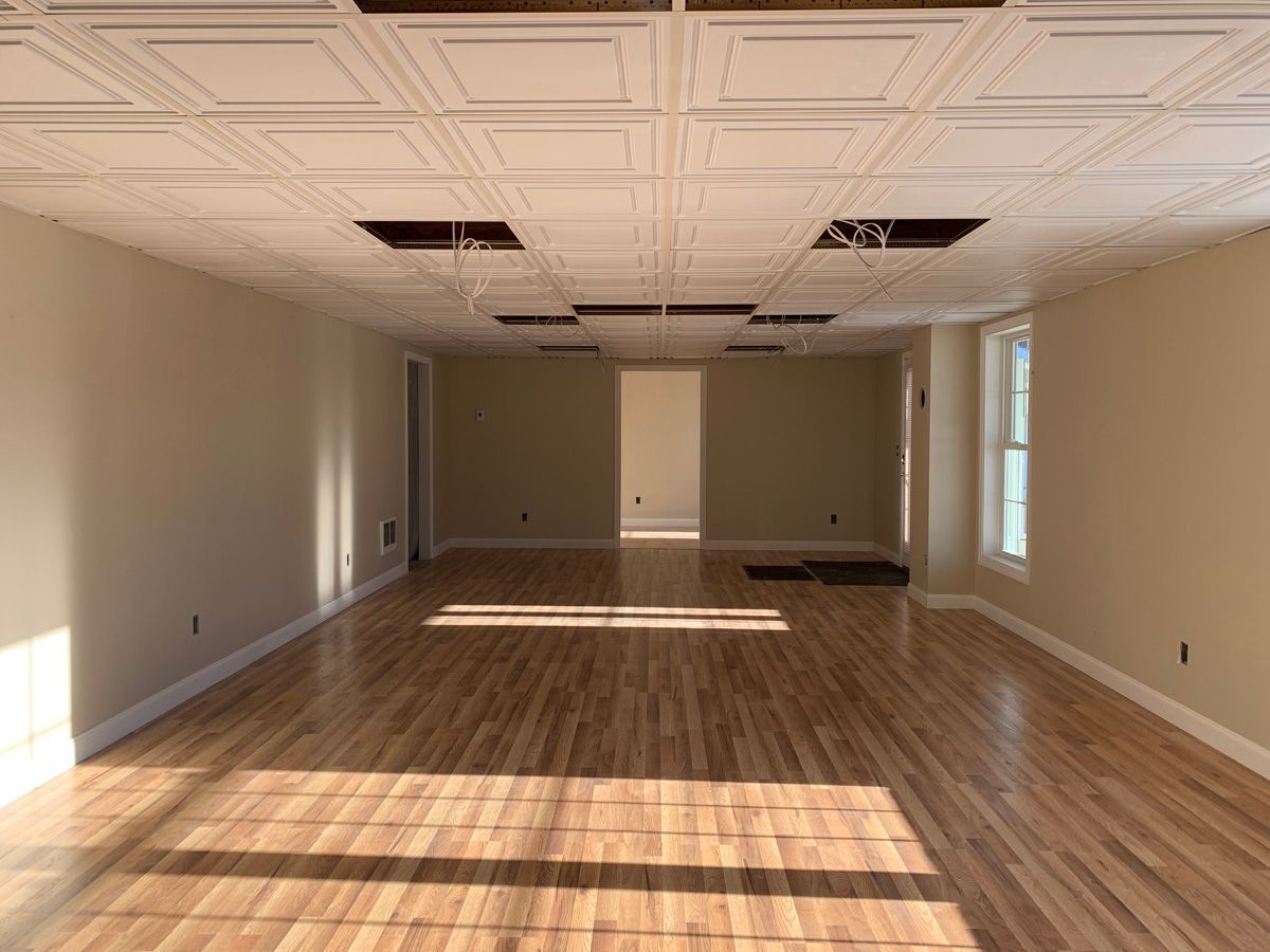 A large empty room with hardwood floors and white walls.