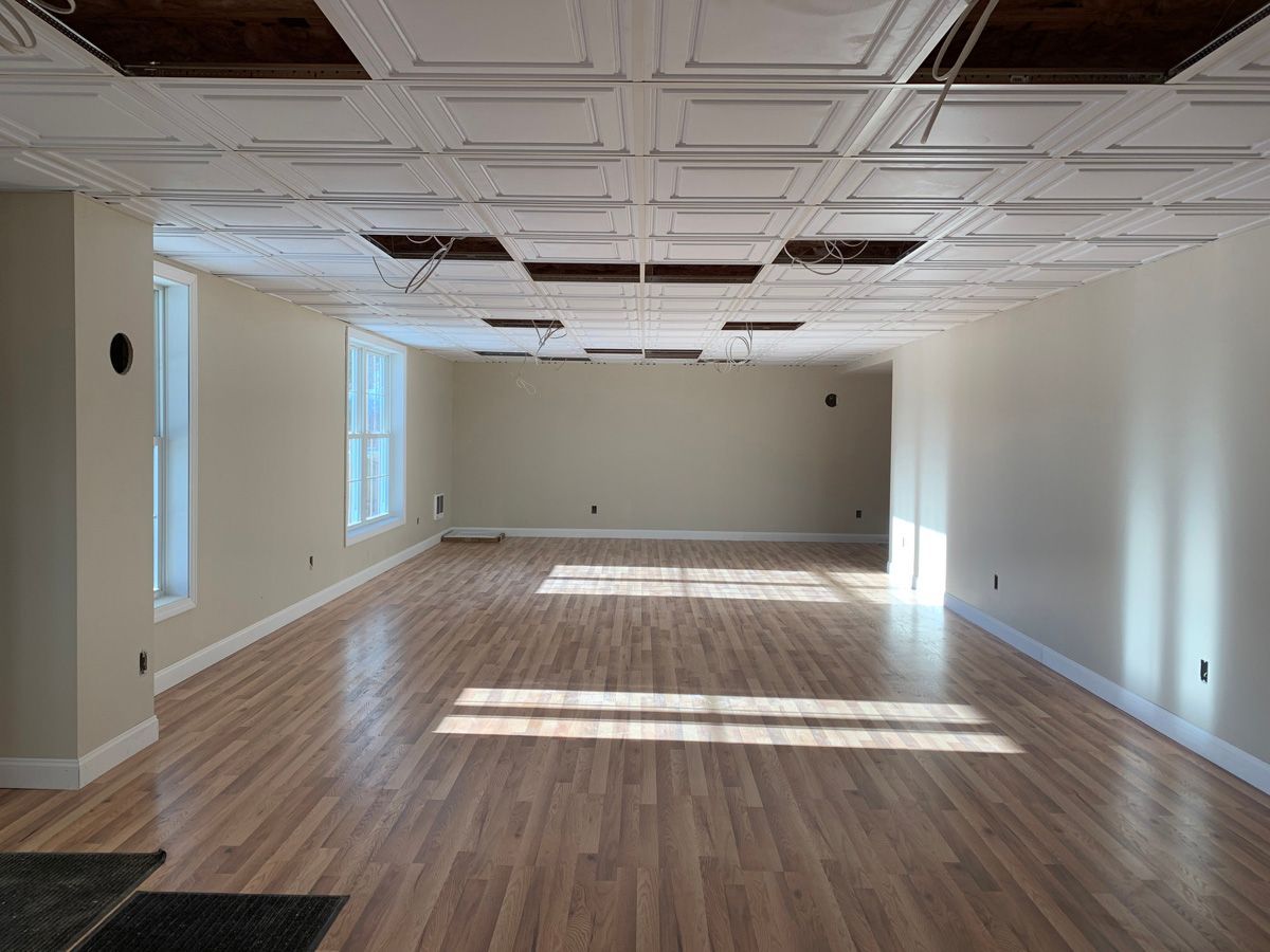 A large empty room with hardwood floors and white walls.