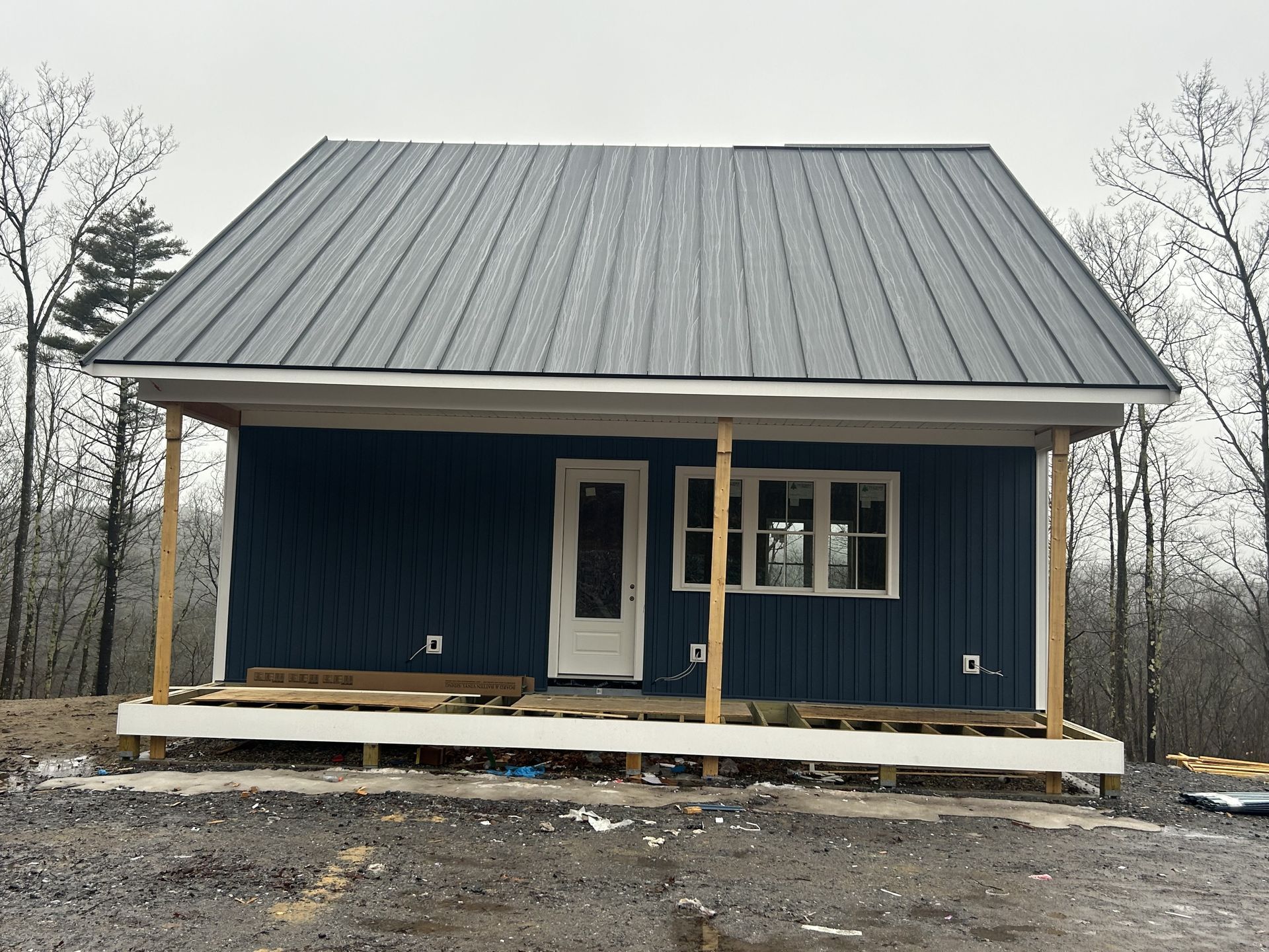 A blue house with a metal roof and a porch