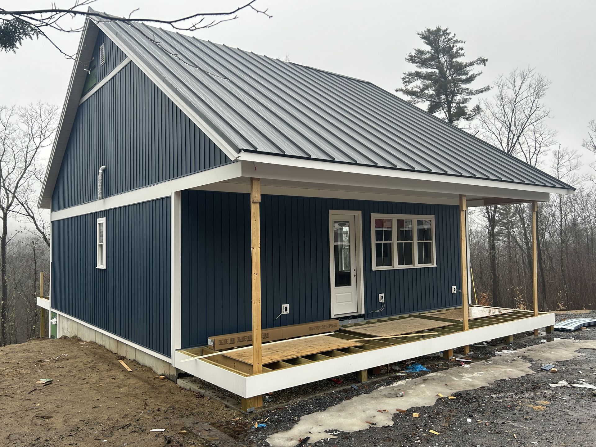 A blue house with a metal roof and a porch.