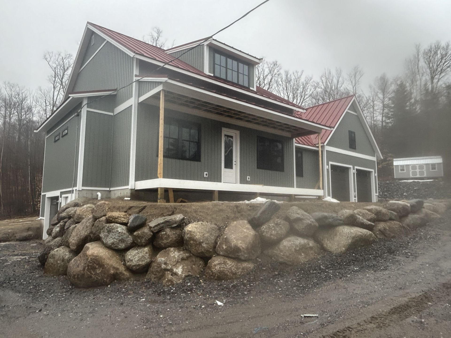 A house with a red roof is sitting on top of a rock wall.