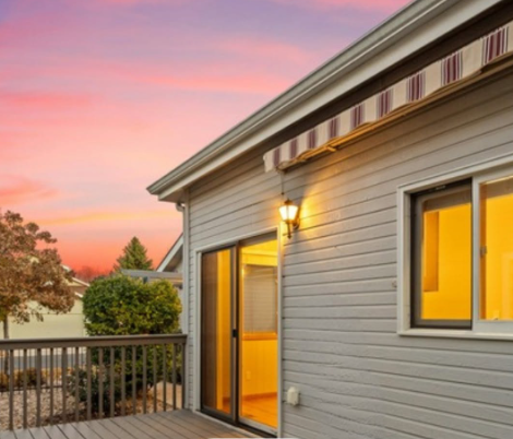 House deck and sliding door at sunset with pink sky and warm indoor light