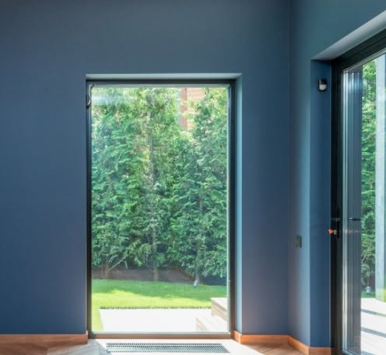 Blue room with open doorway and large window overlooking a green garden
