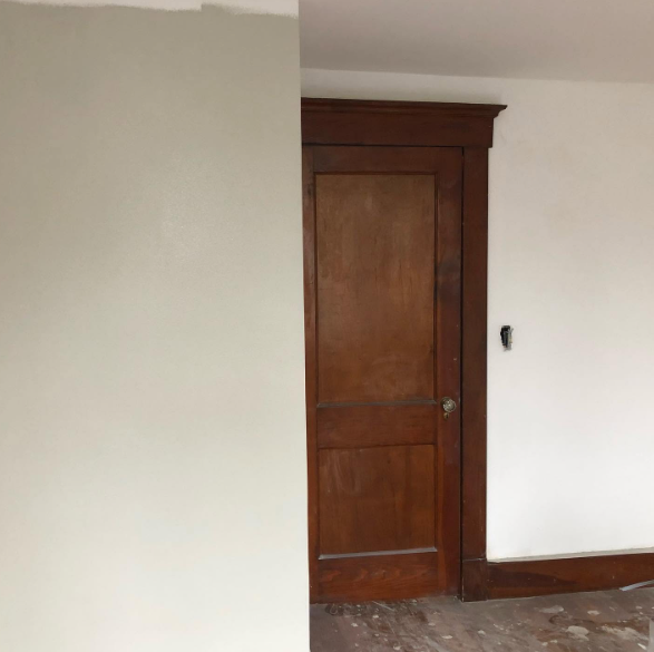 Empty room with beige walls and a closed dark wooden door.