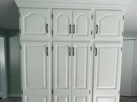 White built-in wardrobe cabinets with multiple paneled doors in a room.