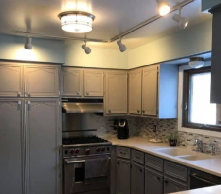 Modern kitchen with gray cabinets, stainless steel stove, and a window over the sink