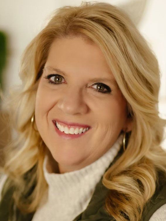Smiling blonde woman in a white turtleneck sweater against a soft beige background