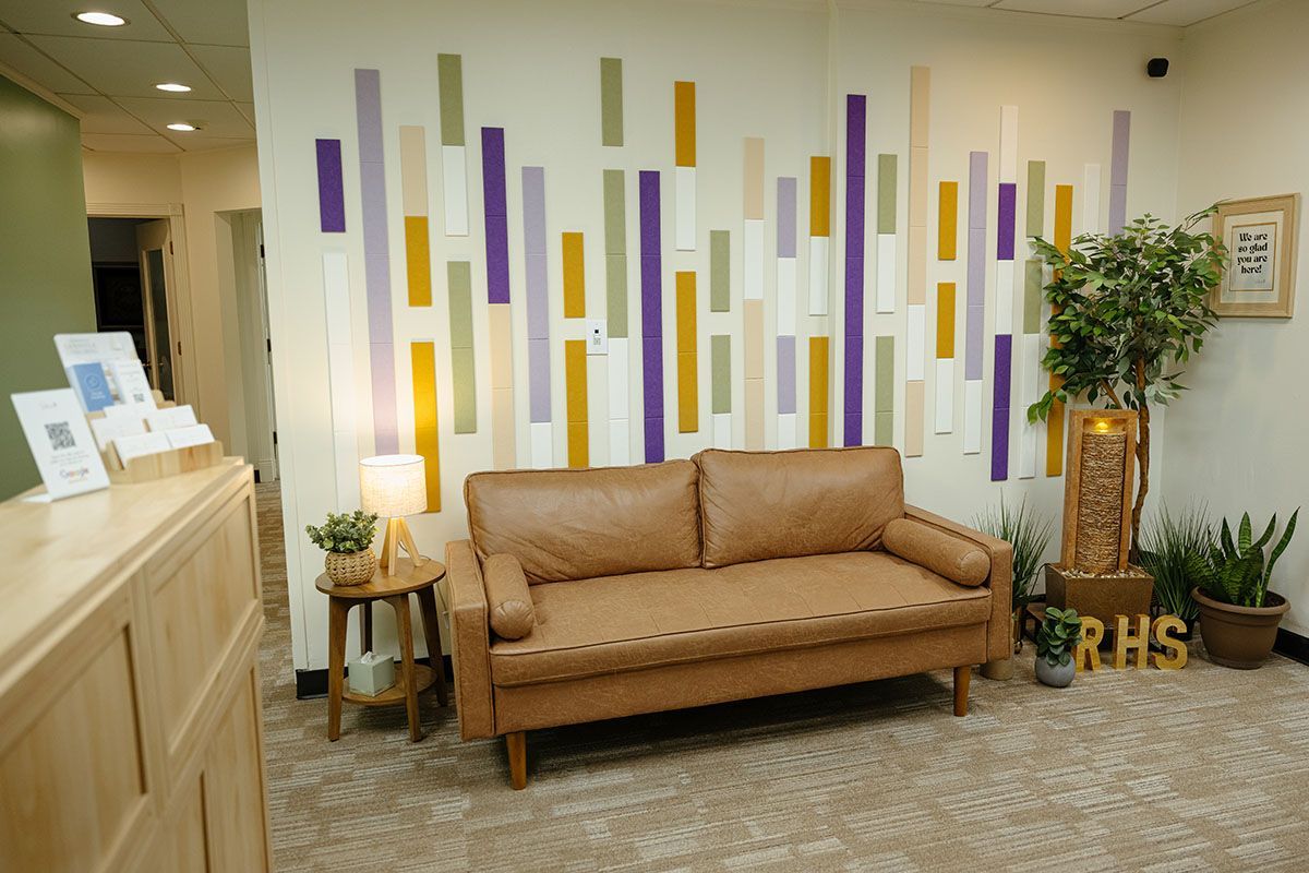 Resilient Health Services lobby with tan sofa, side table lamp, wood reception counter, and colorful wall décor.