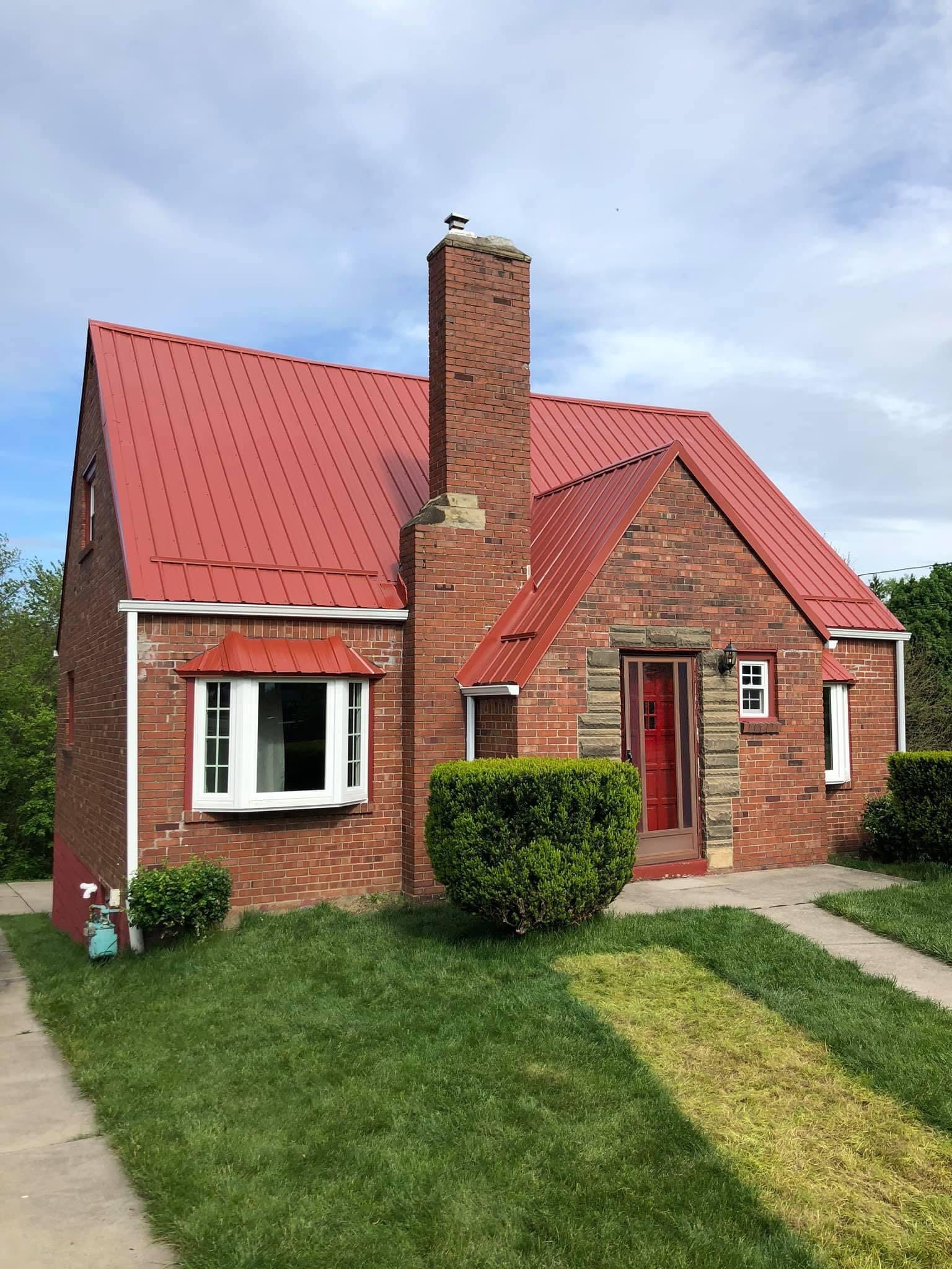 A brick house with a red roof and a chimney.