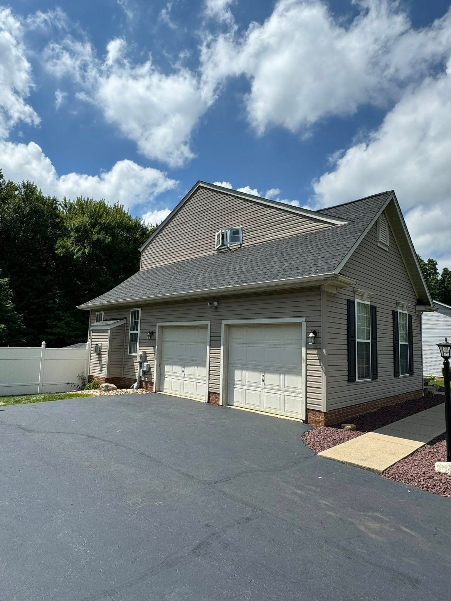 A house with two garage doors and a driveway in front of it.