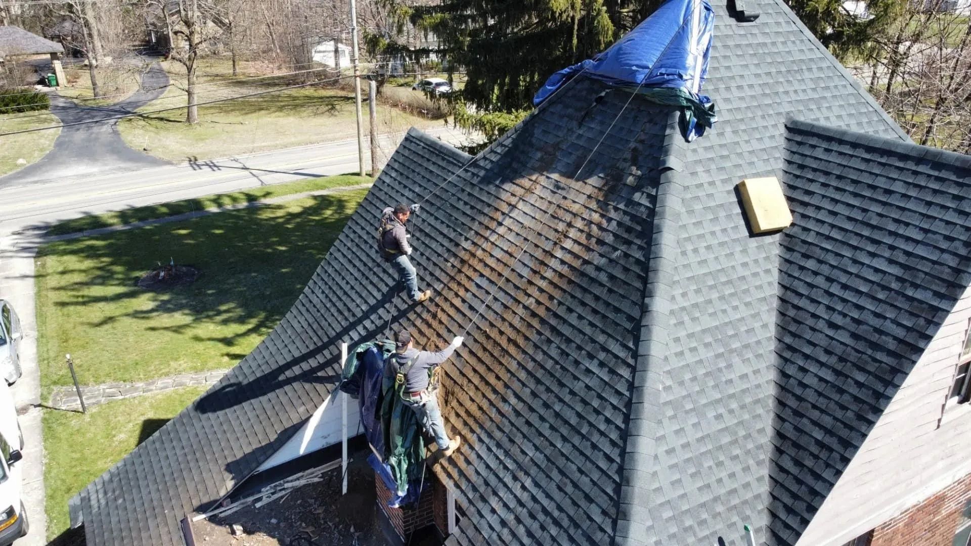 A group of people are working on the roof of a house.