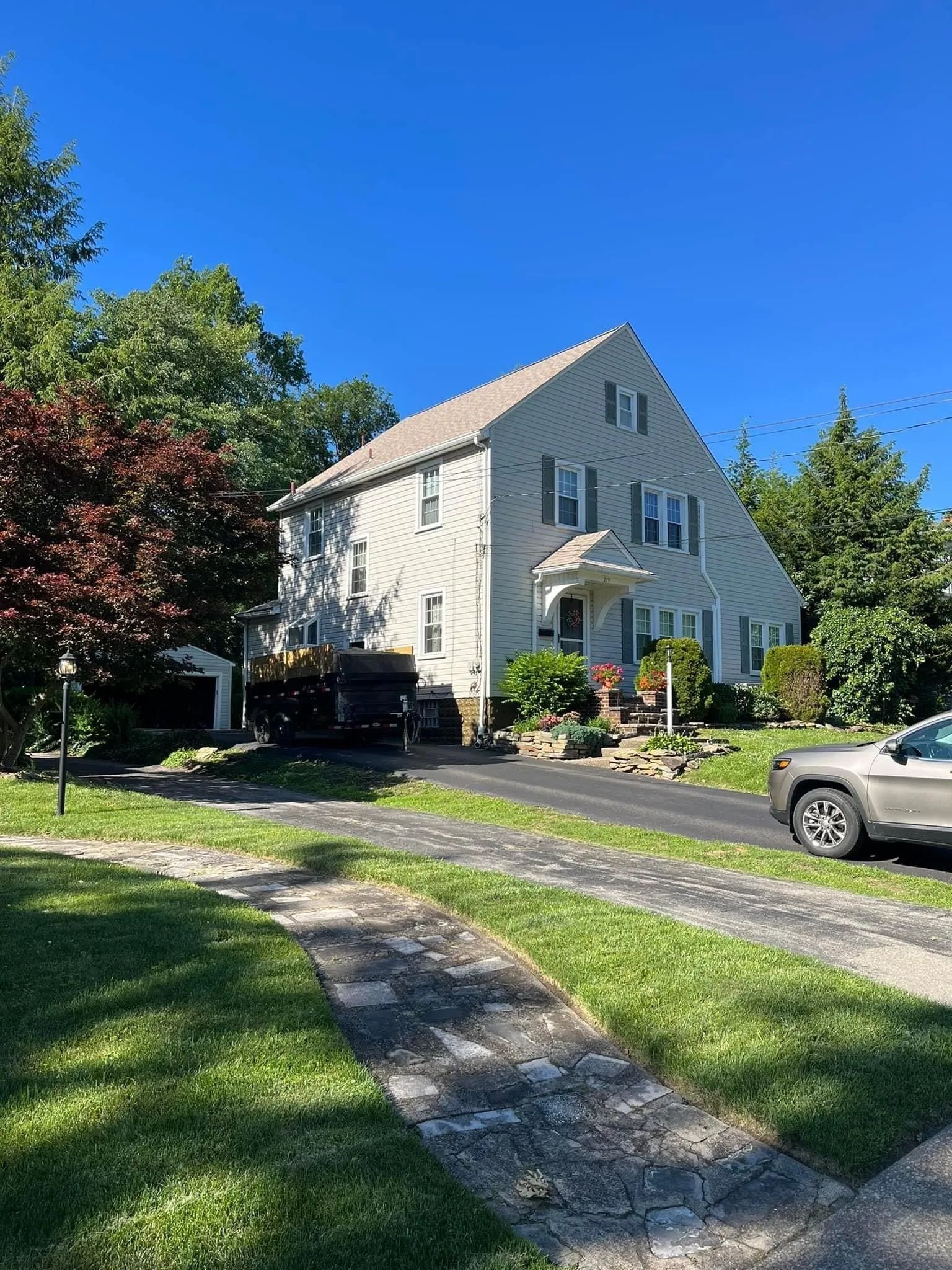 A white house with a car parked in front of it on a sunny day.