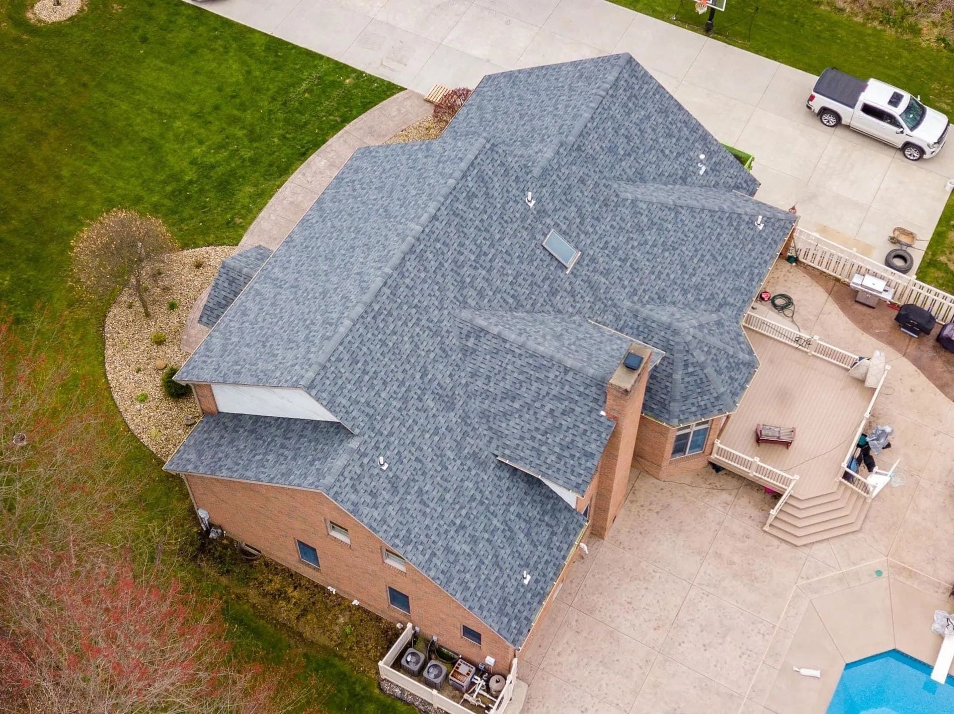 An aerial view of a large house with a blue roof and a pool.