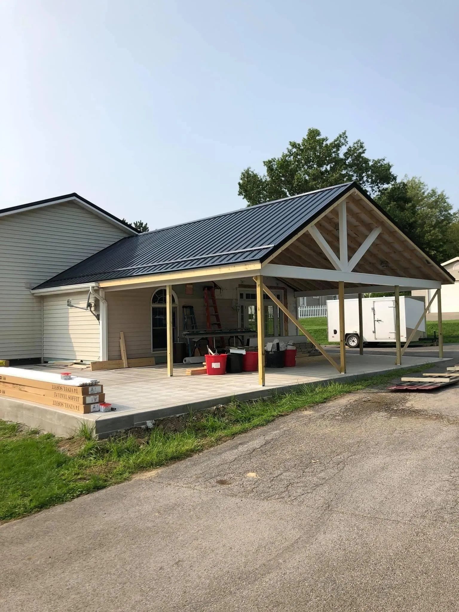 A house with a blue roof is being built next to a road.