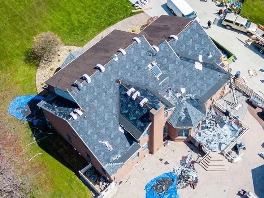 An aerial view of a large house with a roof being installed.