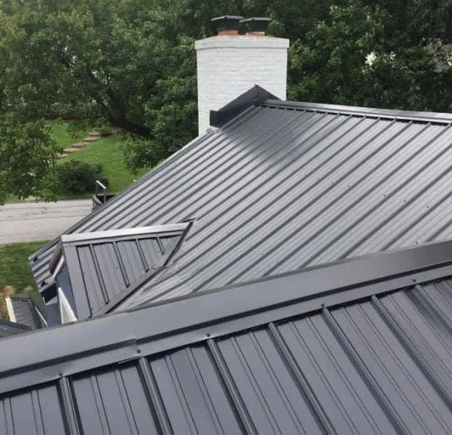 A black metal roof with a chimney on top of it.