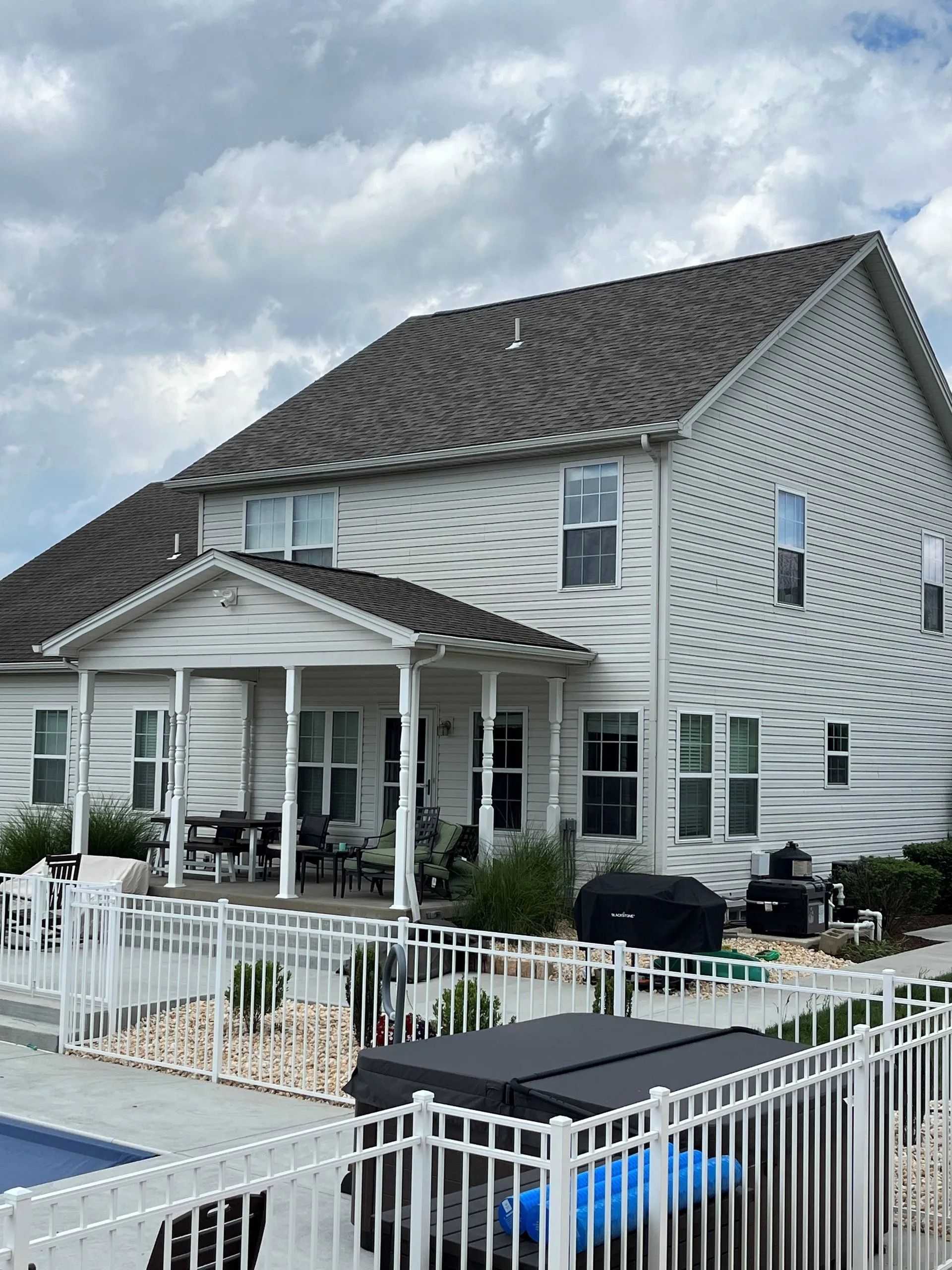 A large white house with a fence around it and a pool.