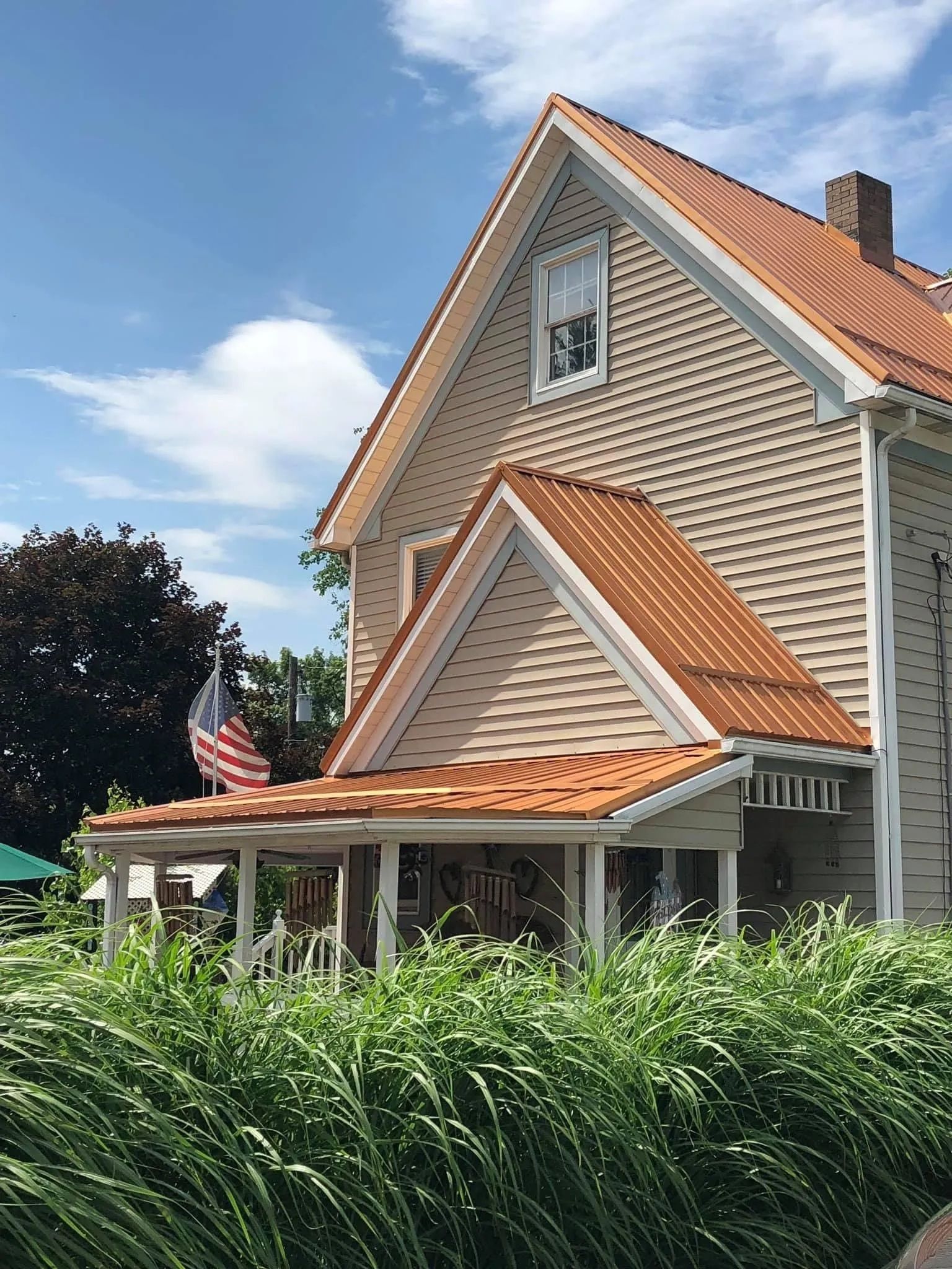 A house with a red tile roof is surrounded by tall grass.