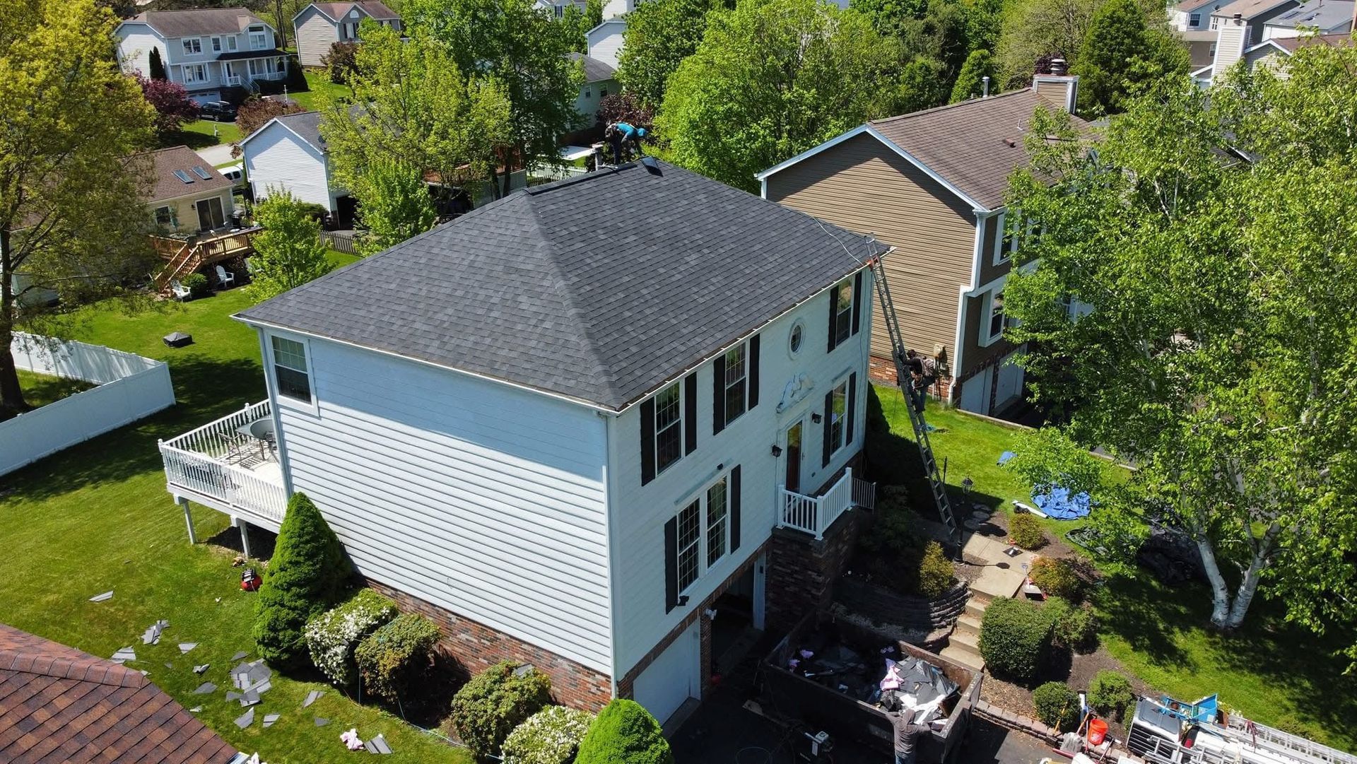 An aerial view of a house with a black roof in a residential area.
