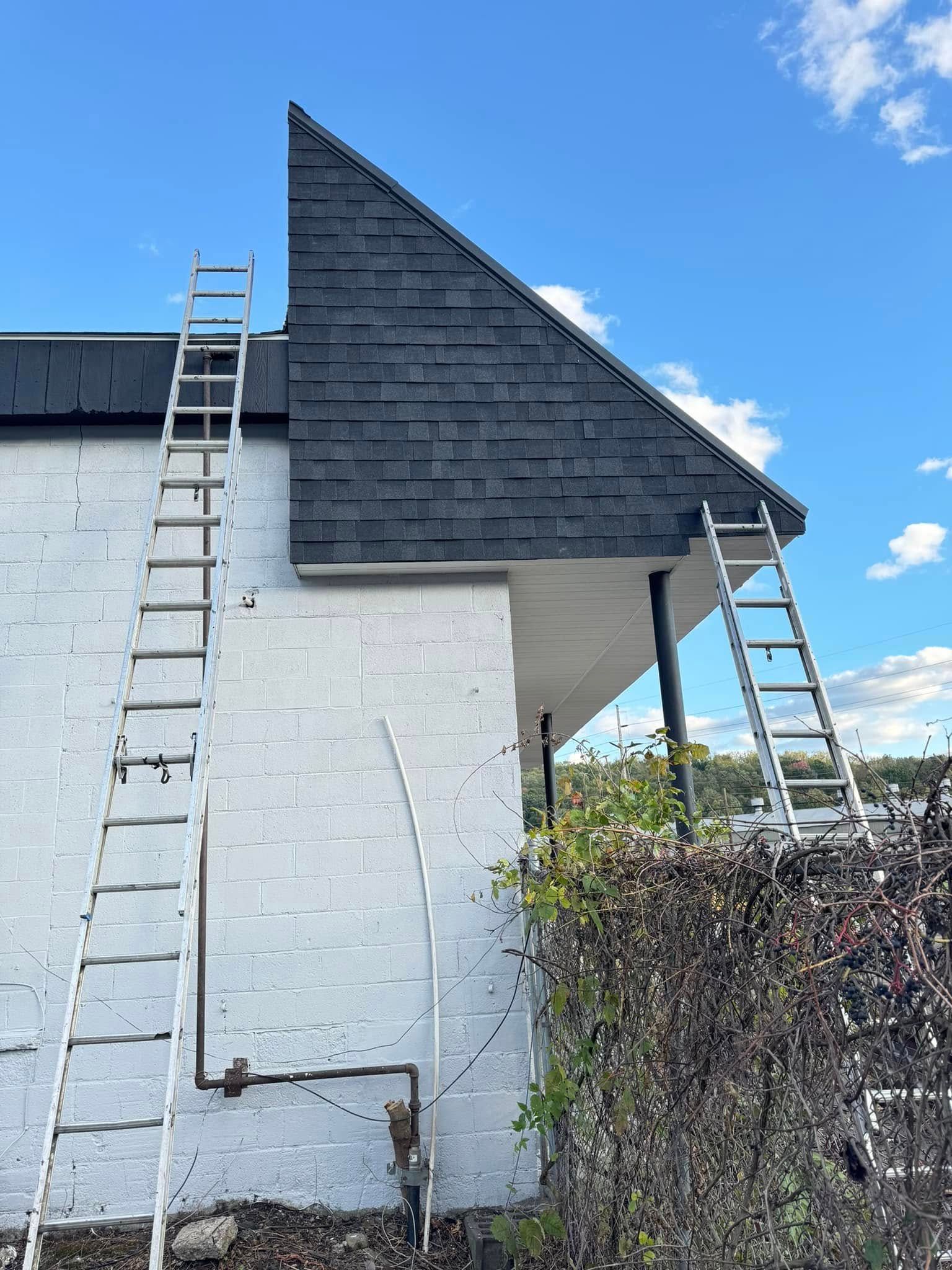 A ladder is sitting on the side of a white brick building.