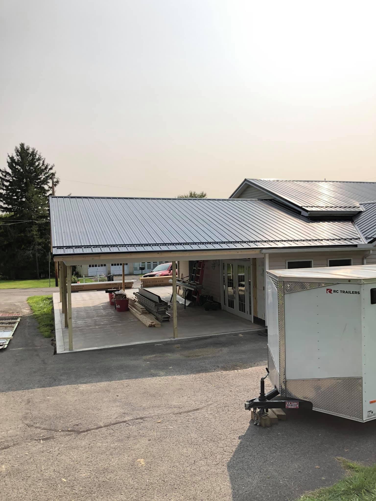 A house with a metal roof and a trailer parked in front of it.