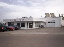 Heating Equipment Co. building with a white exterior, large windows, and an American flag on the front facade.