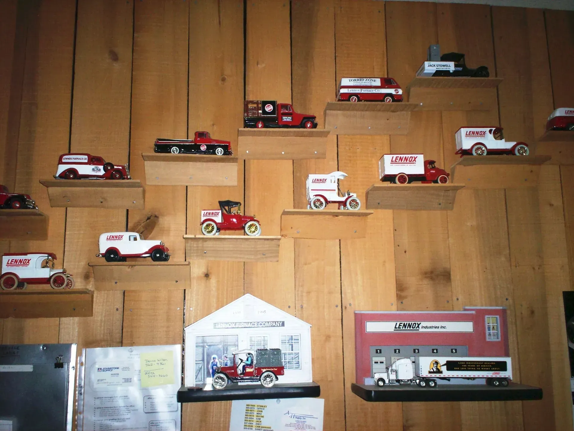 Collection of vintage model trucks displayed on staggered wooden wall shelves against a paneled wood background.