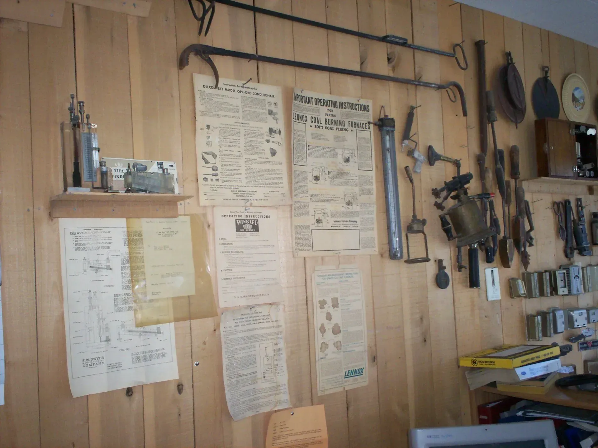 A wood-paneled wall displaying vintage tools, diagrams, and historical informational papers hung in an office setting.