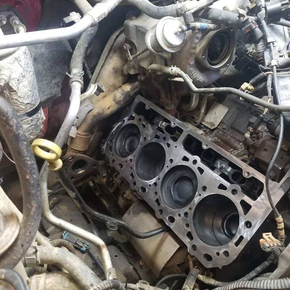 Engine block with cylinder head removed, showing exposed cylinders and internal components during repair.