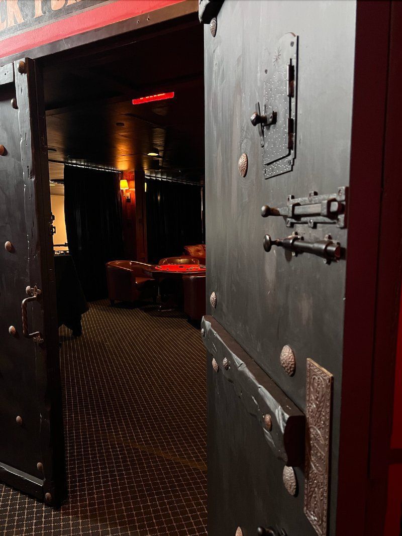 Heavy, dark doors slightly ajar, revealing a dimly lit interior.  The door has metal hardware.