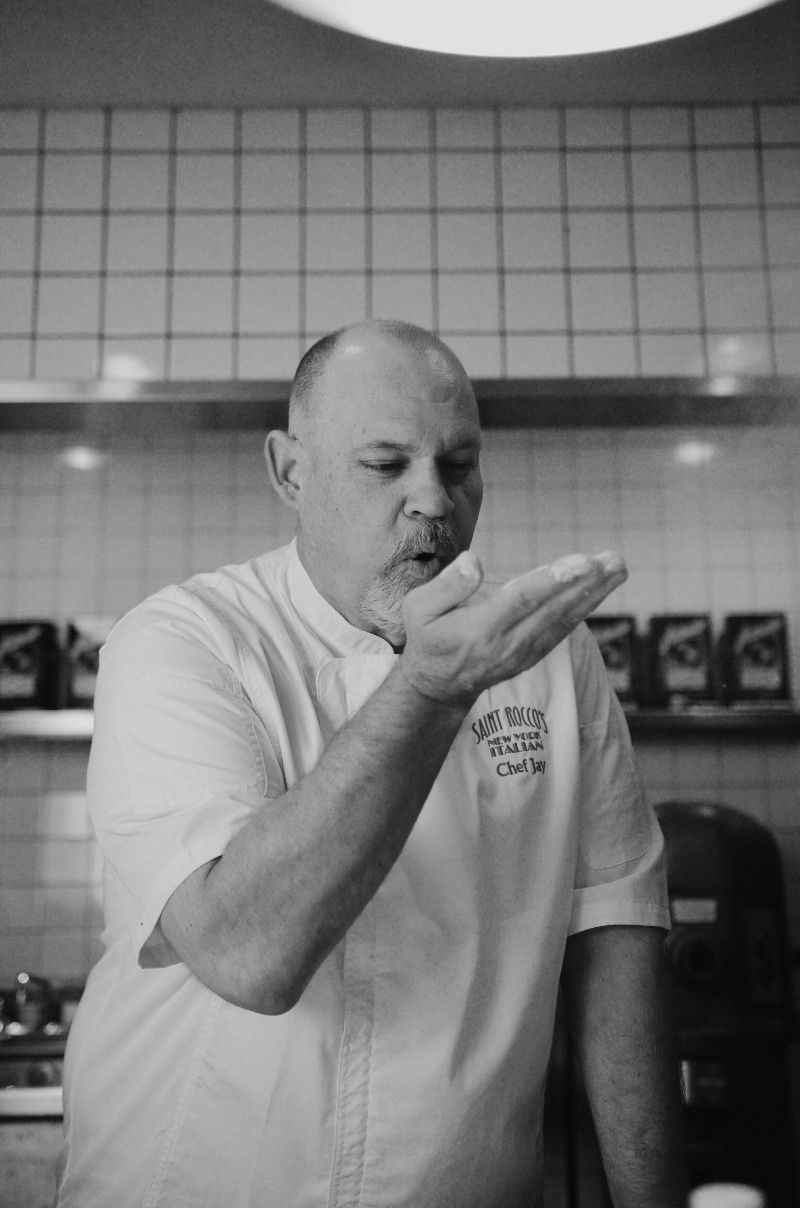 Chef blowing flour from his hand in a kitchen.