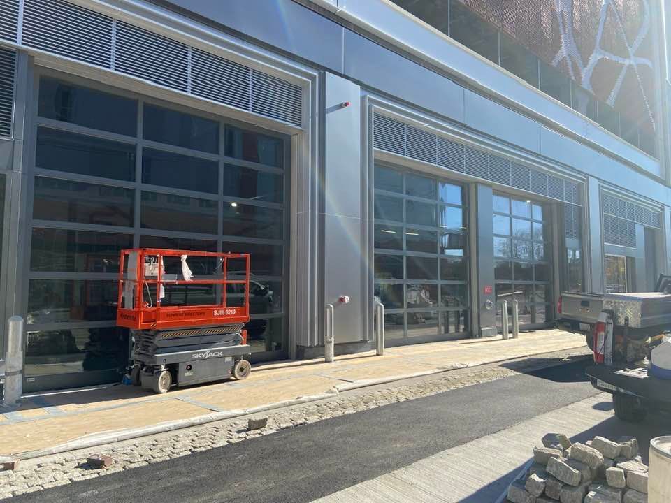 An orange scissor lift is parked in front of a building.