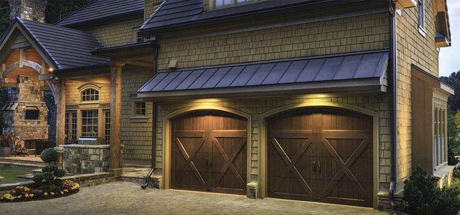 A large house with two wooden garage doors and a metal roof.