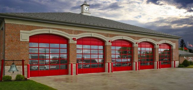 A fire station with red garage doors and a clock on top of it.