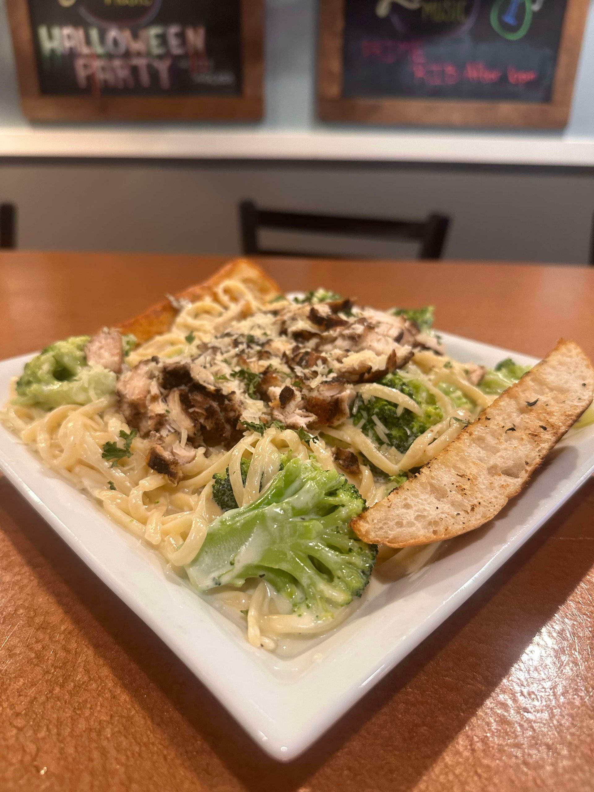A white plate topped with pasta and broccoli on a table.